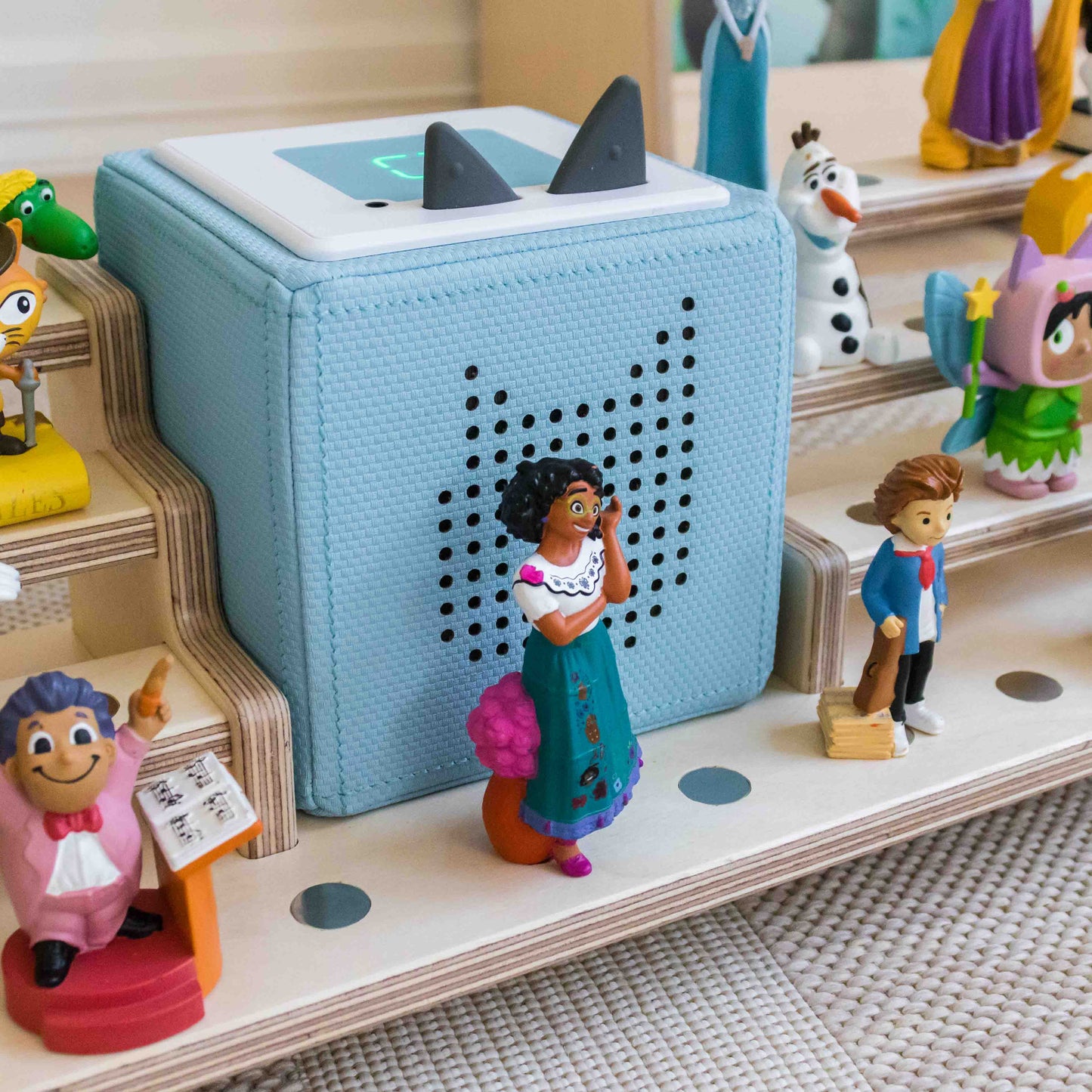 Tonie figures and toniebox sitting on a wooden display.