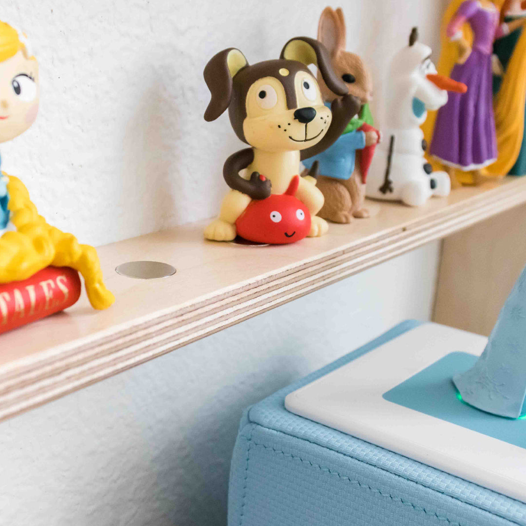 Close up of a wooden tonie shelf showing the built in metal dot design to securely hold tonie characters in place when placed on the shelf.