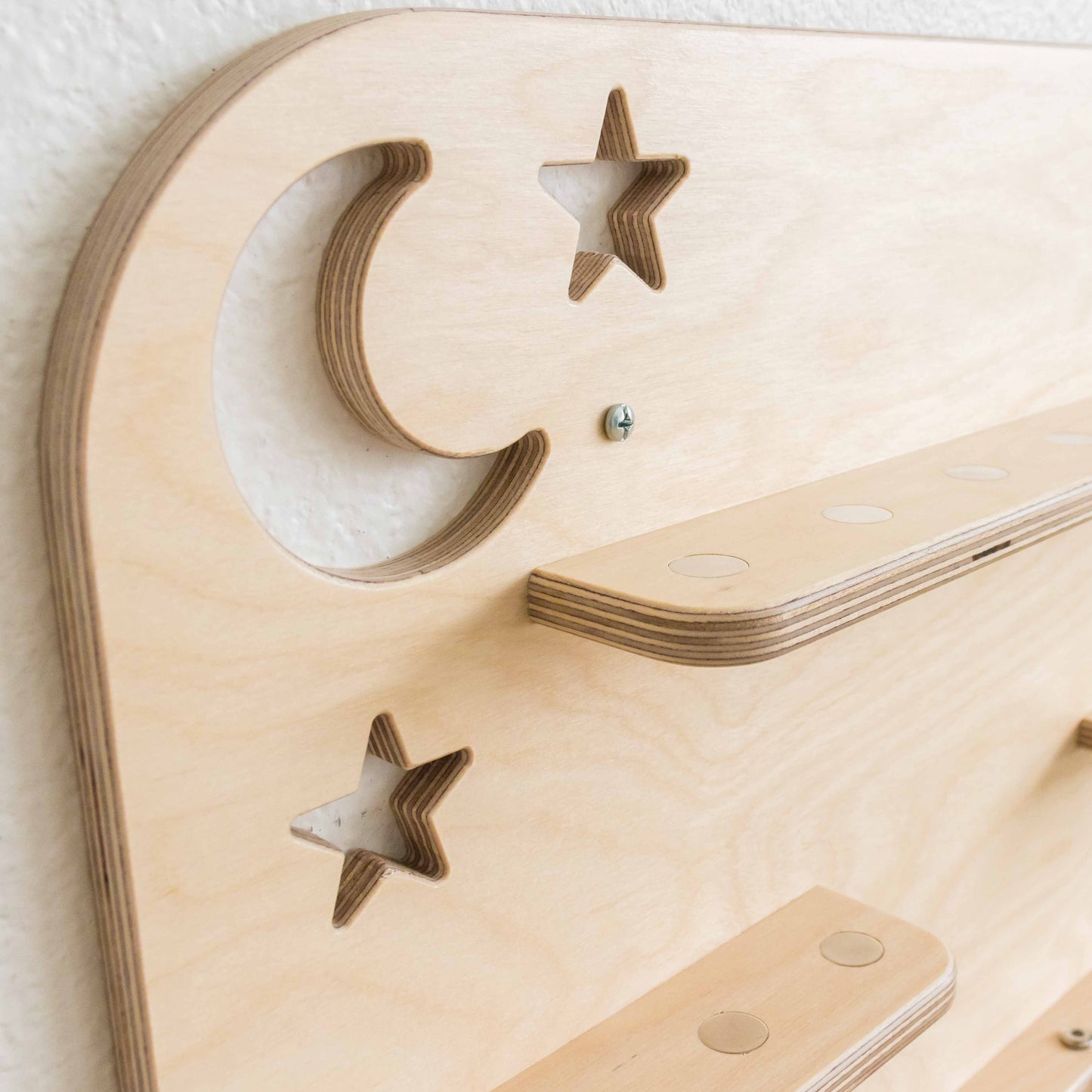 detail of a moon and stars cutout on a wooden tonie shelf.