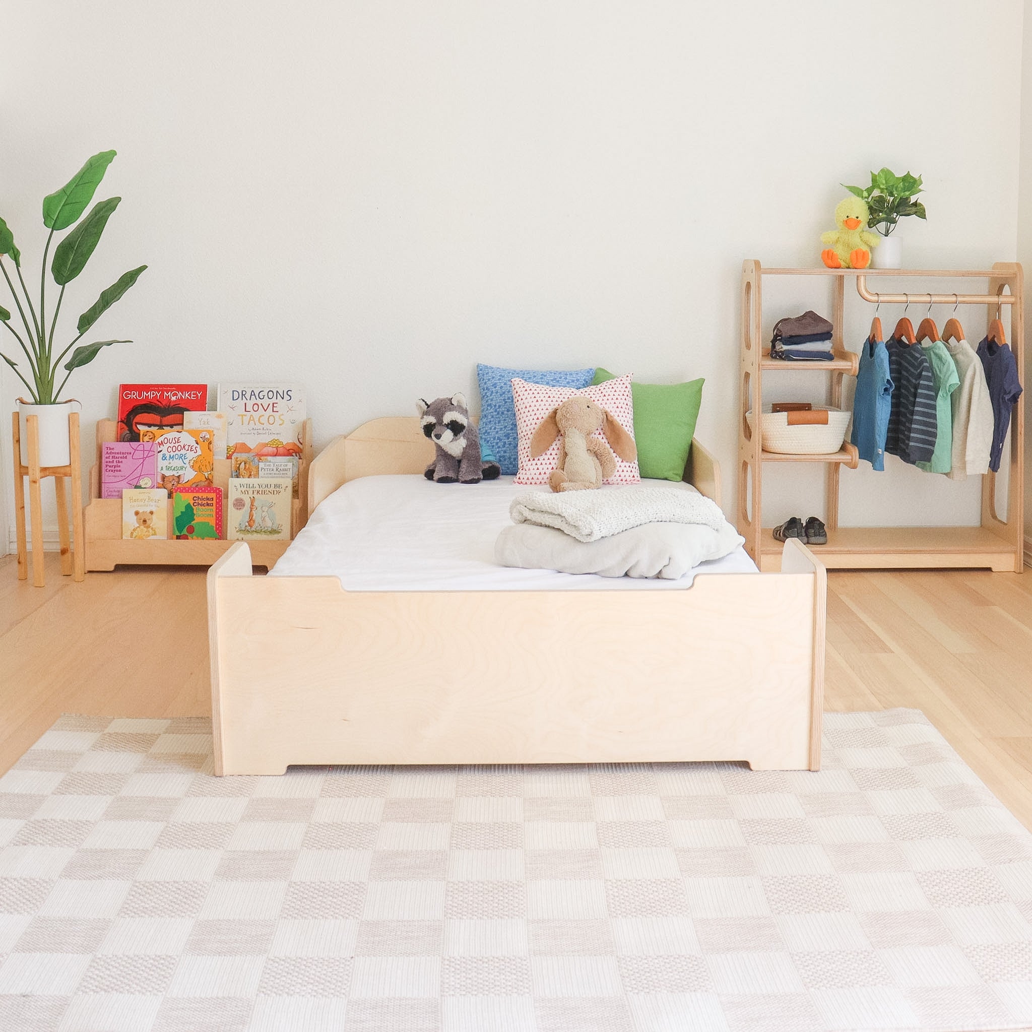 Children's Montessori room with a floor bed, bookshelf , and toys in a bright and organized space.