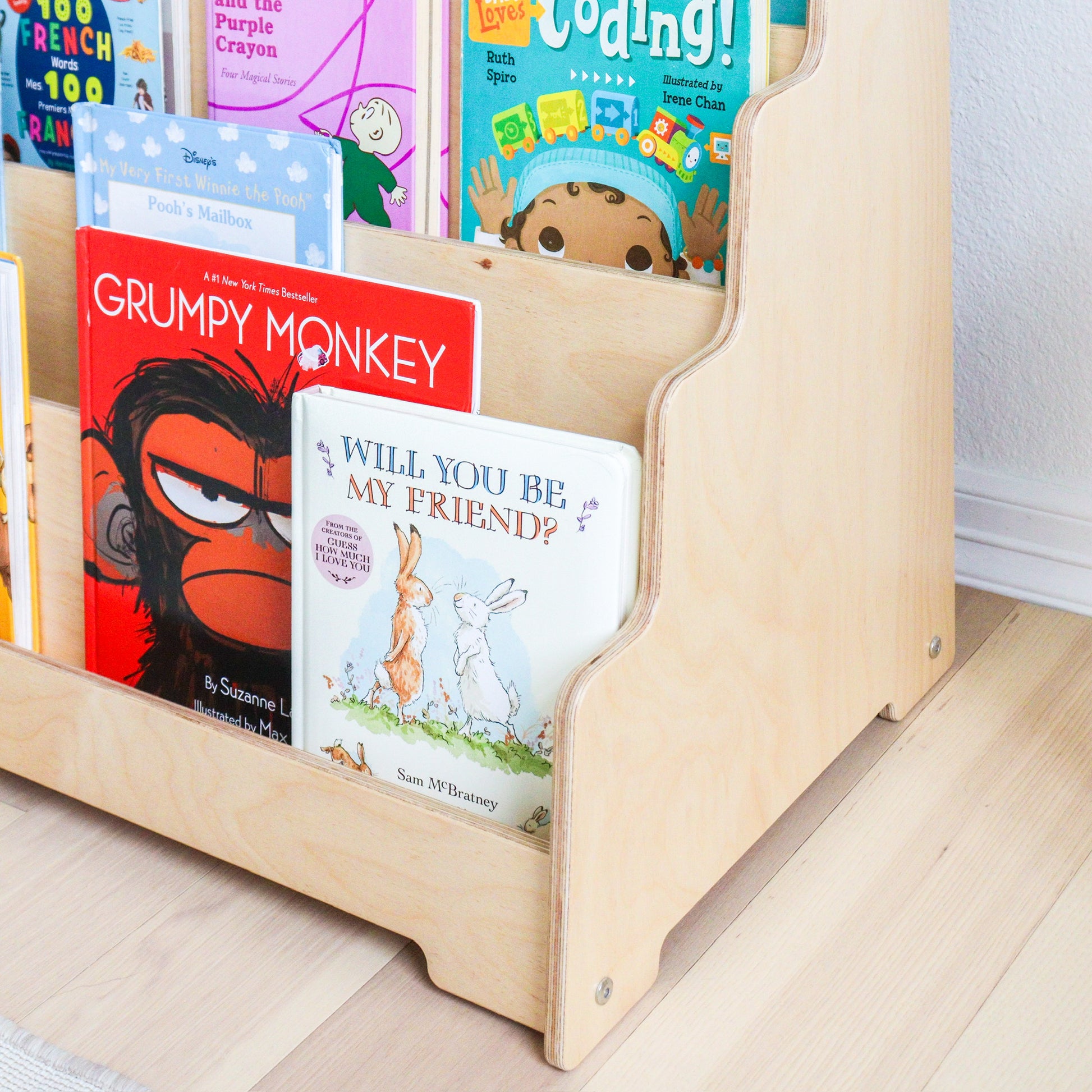 Wooden bookshelf with children's books on a light wooden floor.