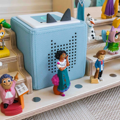 Tonie figures and toniebox sitting on a wooden display. 