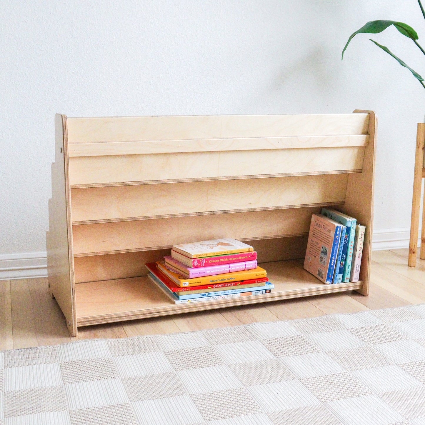 Wooden children's bookshelf with books on a light wooden floor.