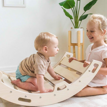 Two children playing on a wooden rocker arch.