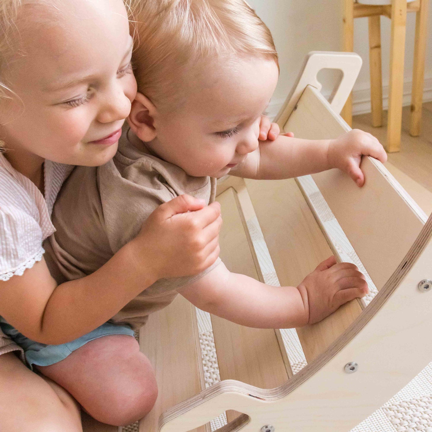 Children playing on a wooden rocking arch.