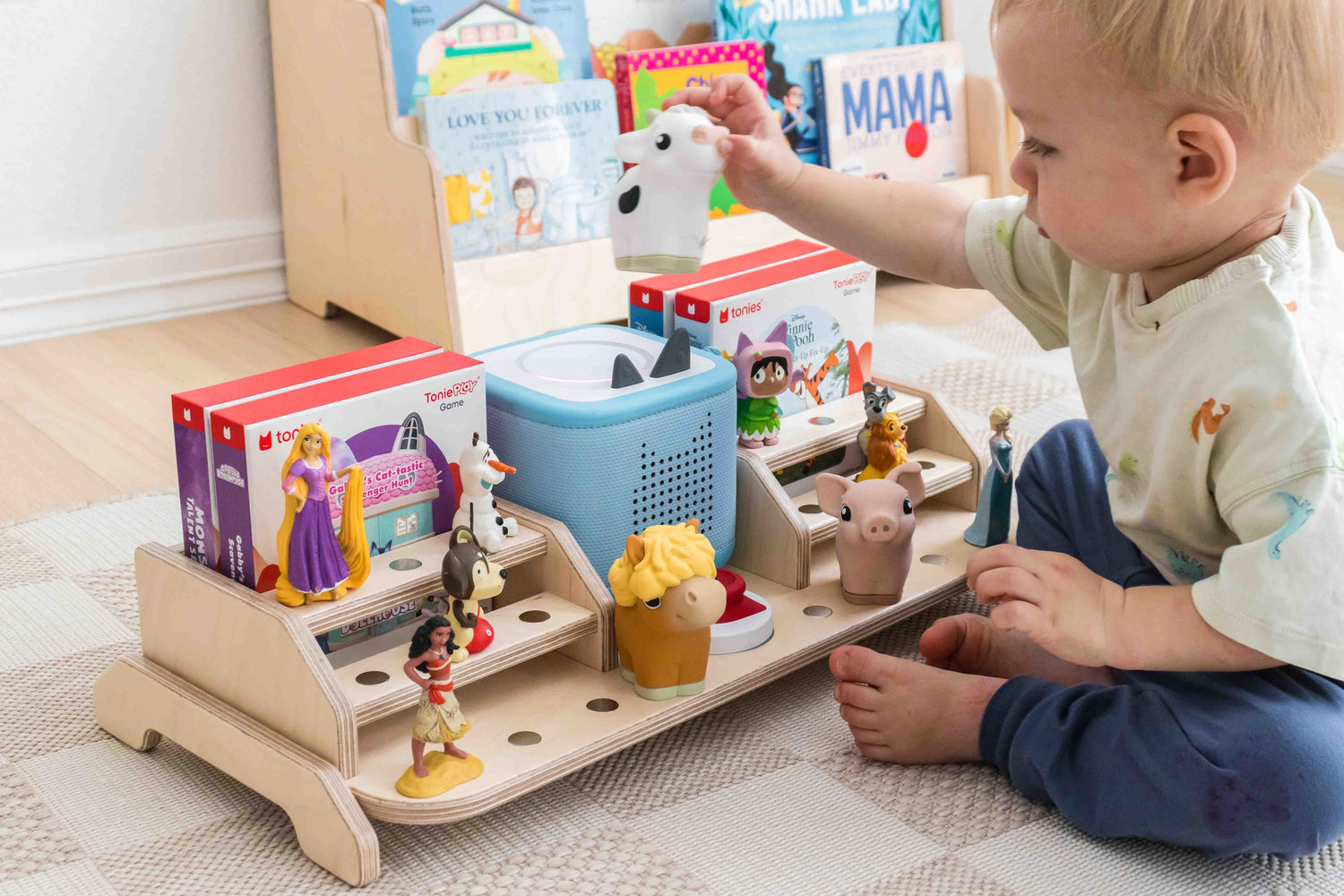 Child playing with tonies on a toniebox 2 storage display. 
