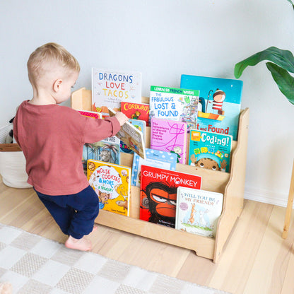 Child browsing books on a wooden bookshelf in a home setting