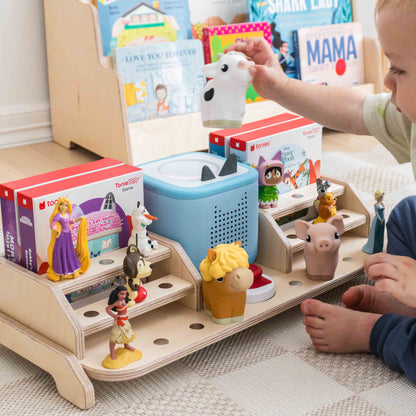 Child playing with tonies on a toniebox 2 storage display. 