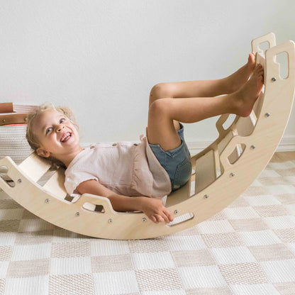 Child laughing while using a wooden rocking arch in a home setting