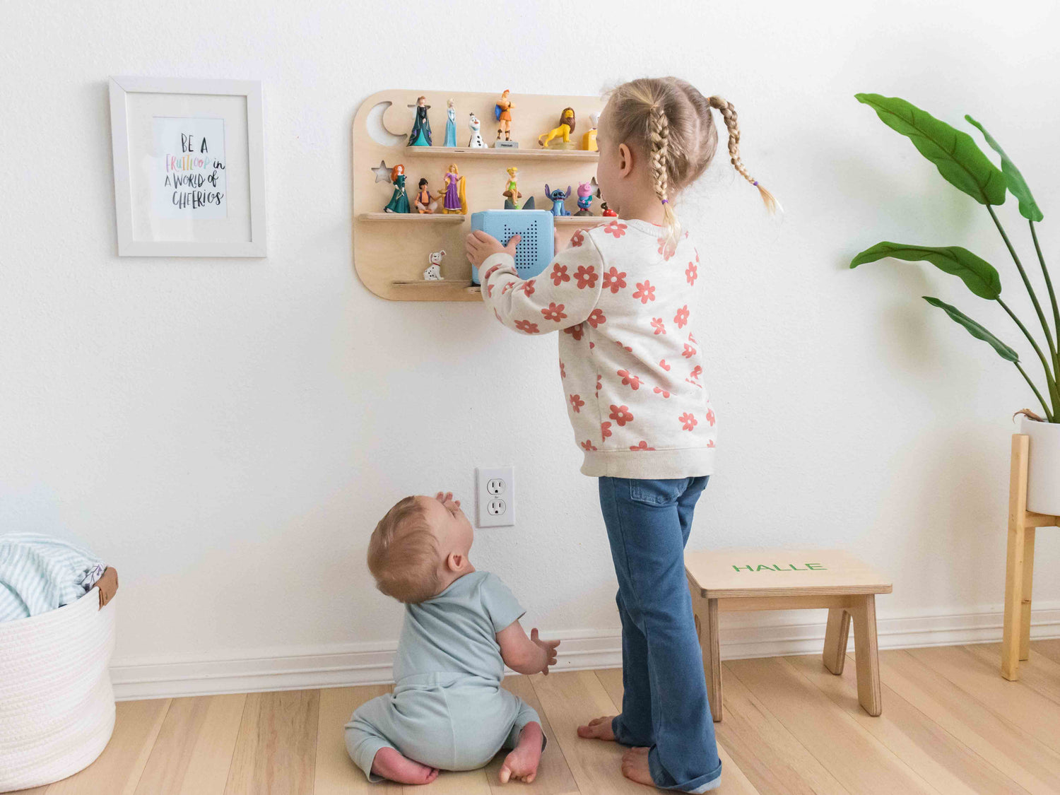 Children playing with a toniebox and tonie figures on a wall mounted shelf