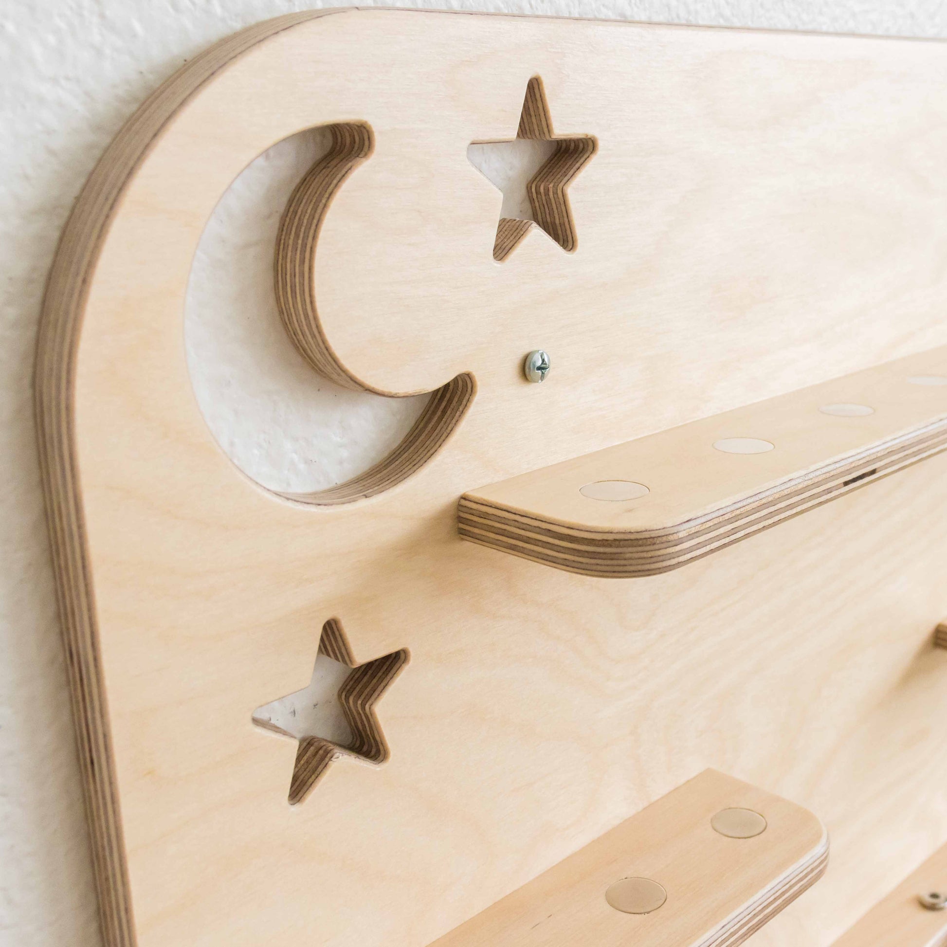 detail of a moon and stars cutout on a wooden tonie shelf. 