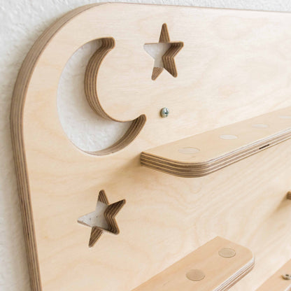 detail of a moon and stars cutout on a wooden tonie shelf. 