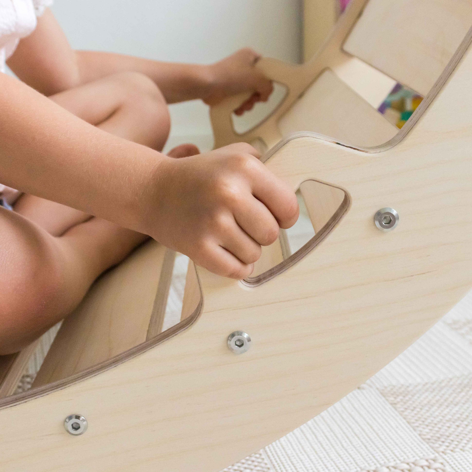 Child's hand holding onto a wooden rocking arch