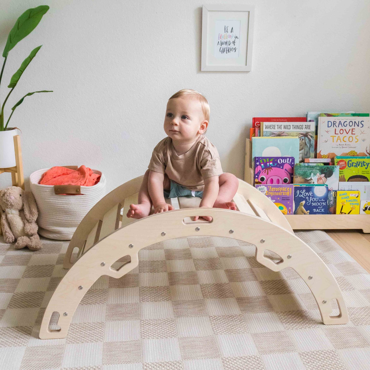 Baby sitting on a wooden climbing arch made from baltic birch. 