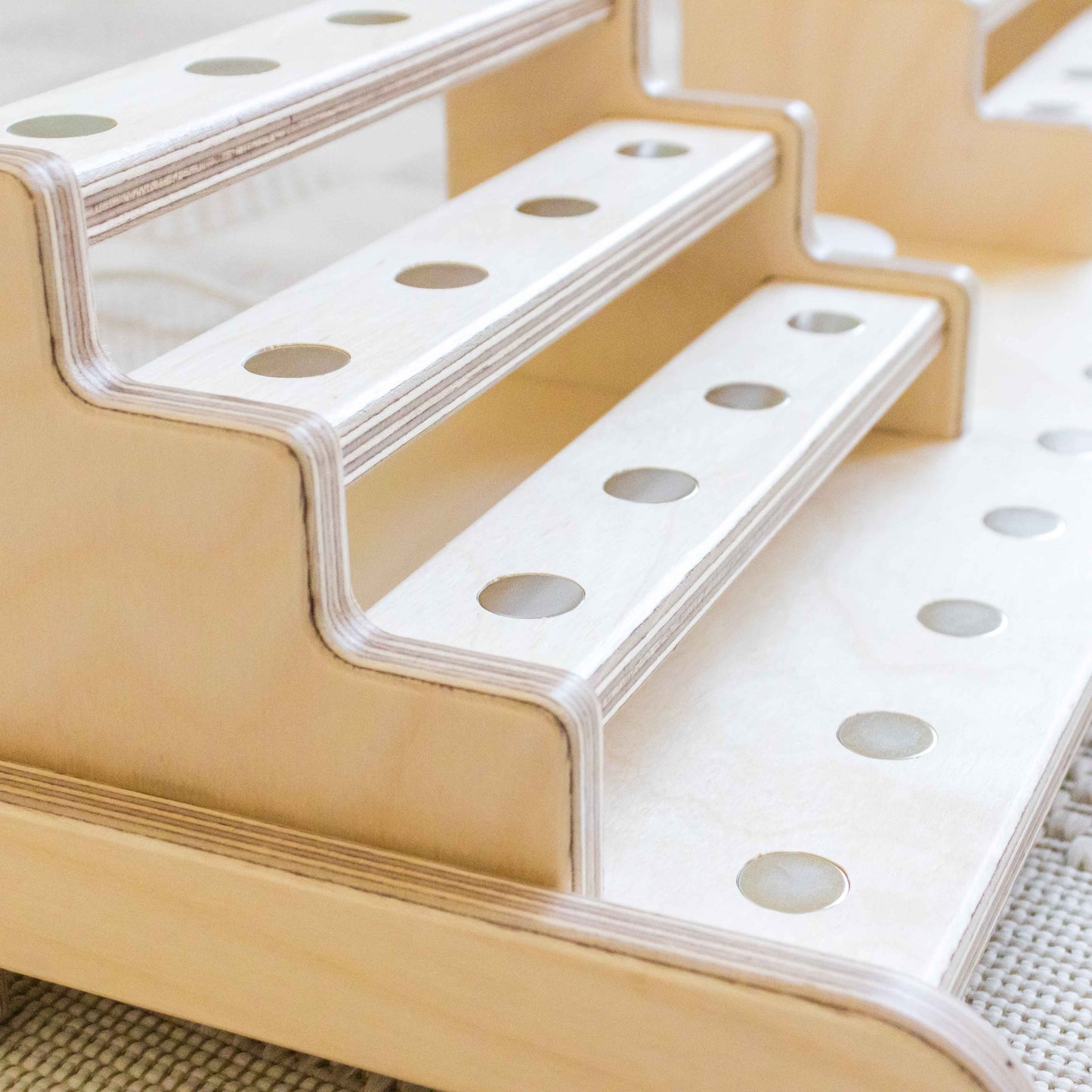 Recessed metal dots in a wooden display designed to hold magnetic tonie figures in place. 